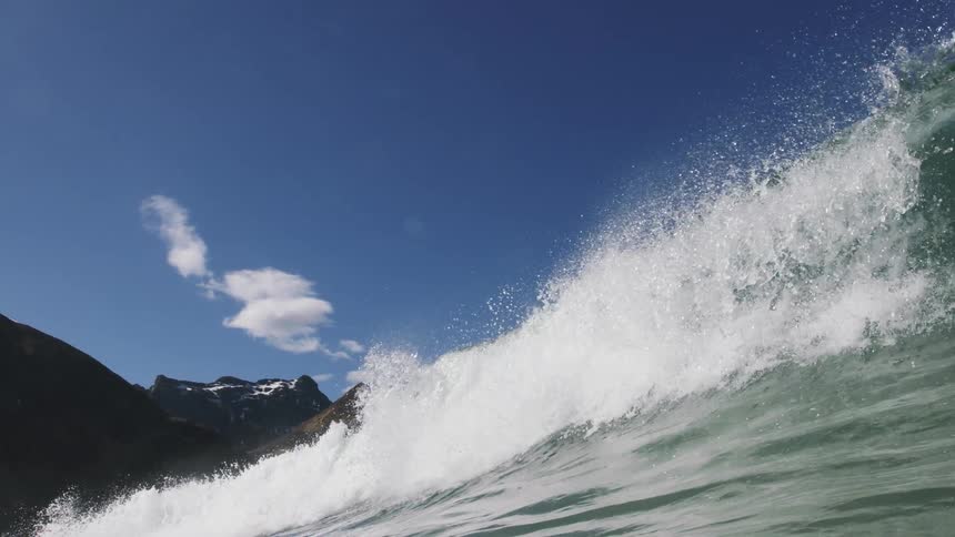 Large foamy waves crash near the mountains