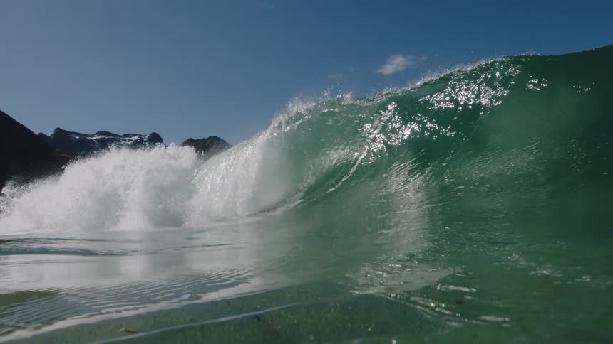 A wave is crashing on a sunny day