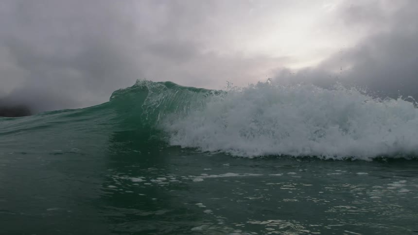 A wave crests and crashes as it rolls toward the shore