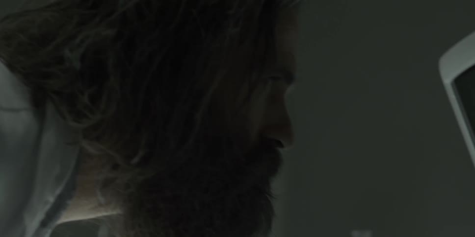 A man in a lab coat is looking at a monitor