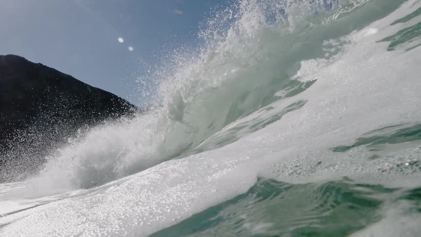 A wave crests and crashes as it rolls toward the shore