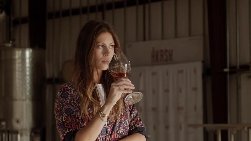 A woman swirls and smells a glass of wine