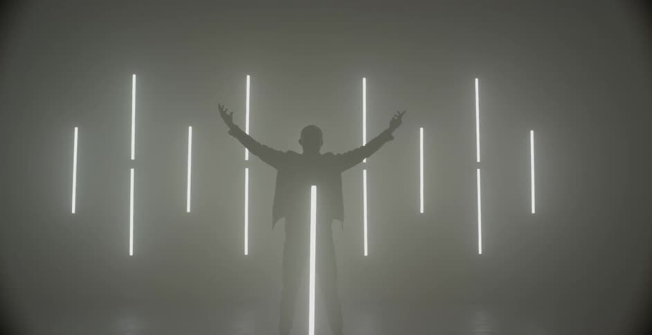 Man lifts arms into the air while surrounded by lights