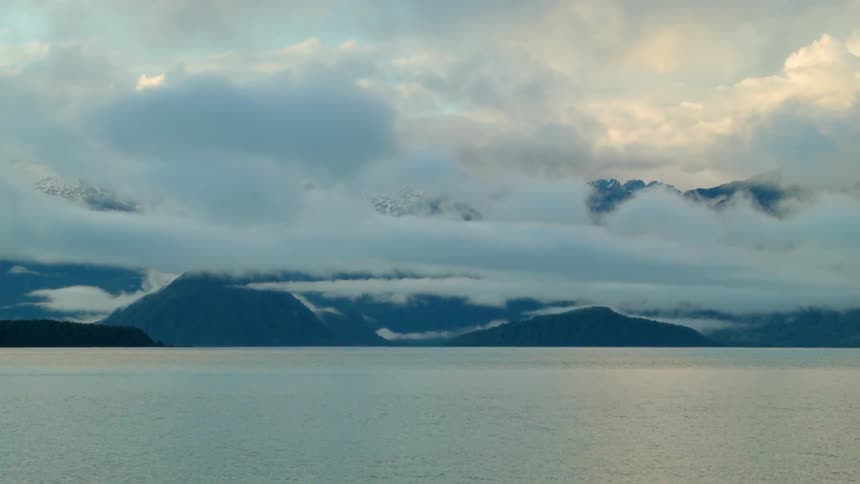 Clouds hang low over a mountainous coastline