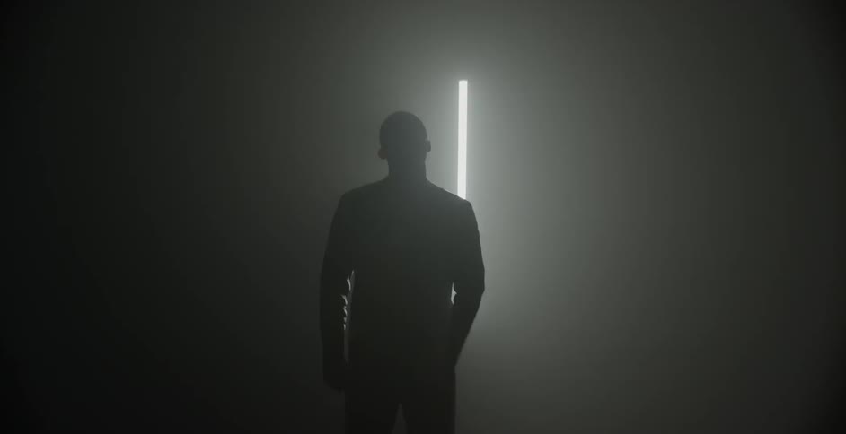 A man gestures and dances in a dim room