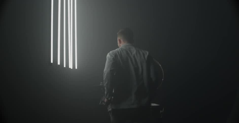 A man is enthusiastically playing drums in a dark room