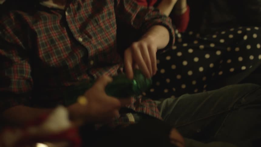 Christmas gift exchange with several people and a man opening a gift