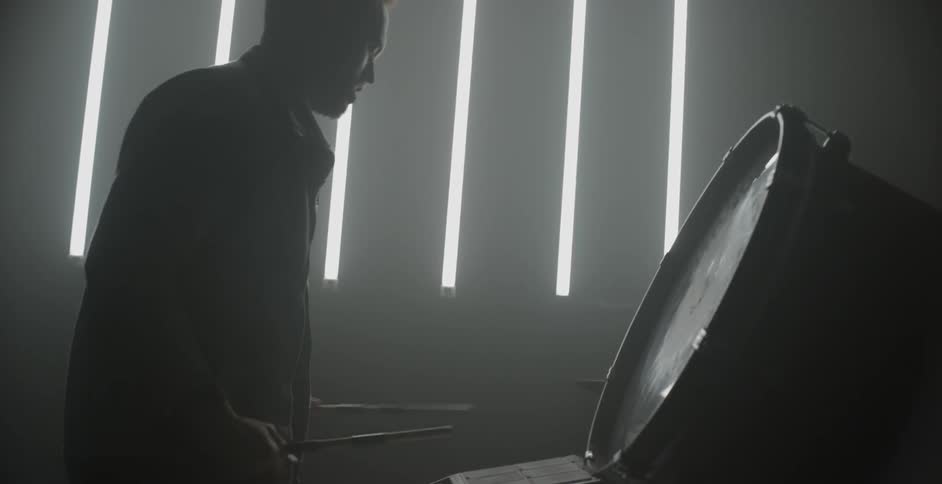 Man uses drumsticks on a big drum