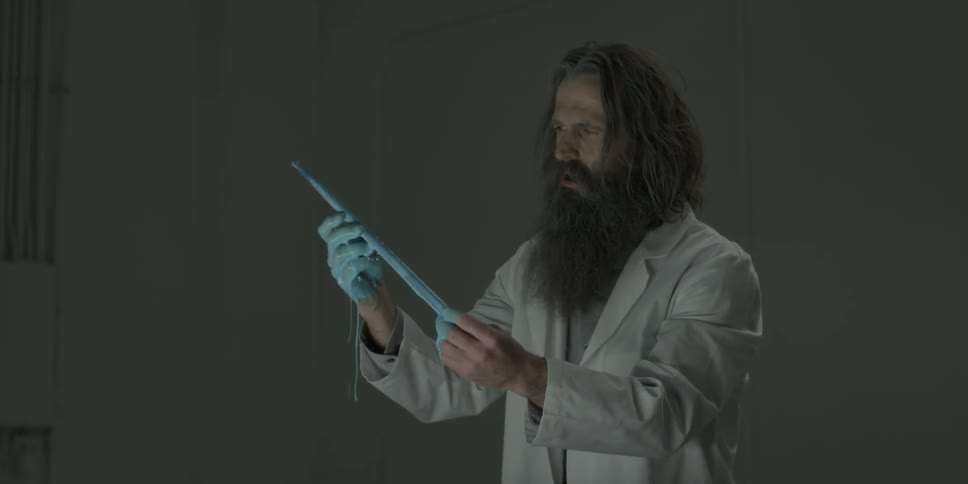 A scientist is pulling a drumstick from some blue liquid and examining it