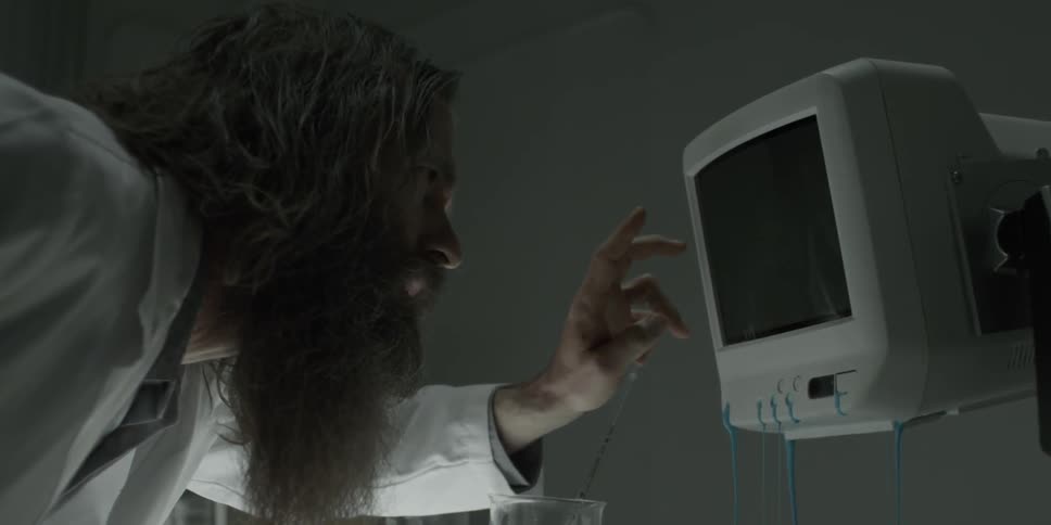 Man in lab coat taps a black screen