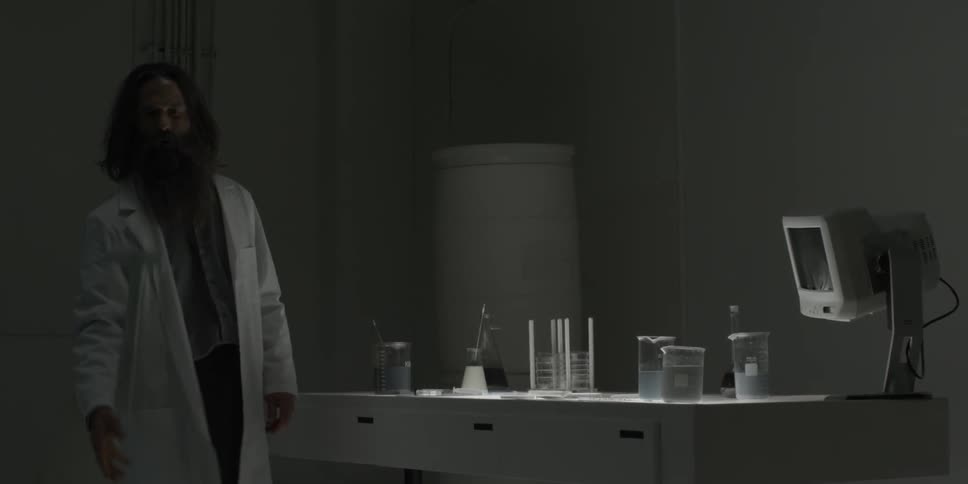 A scientist picks up a rubber mallet and fakes tossing it at a monitor