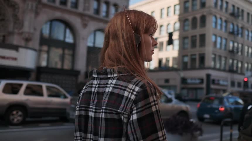 A red haired woman walks outside in the city