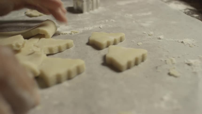 Hands shown in close up cutting out christmas tree cookies