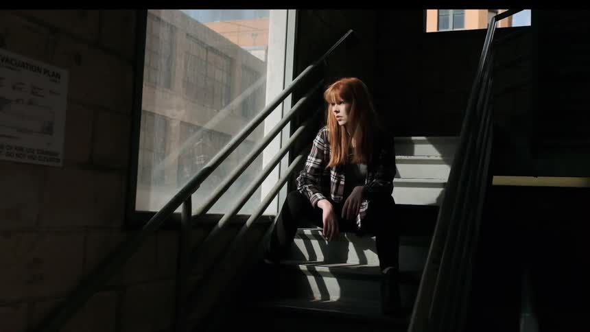 A red haired woman sits on the steps