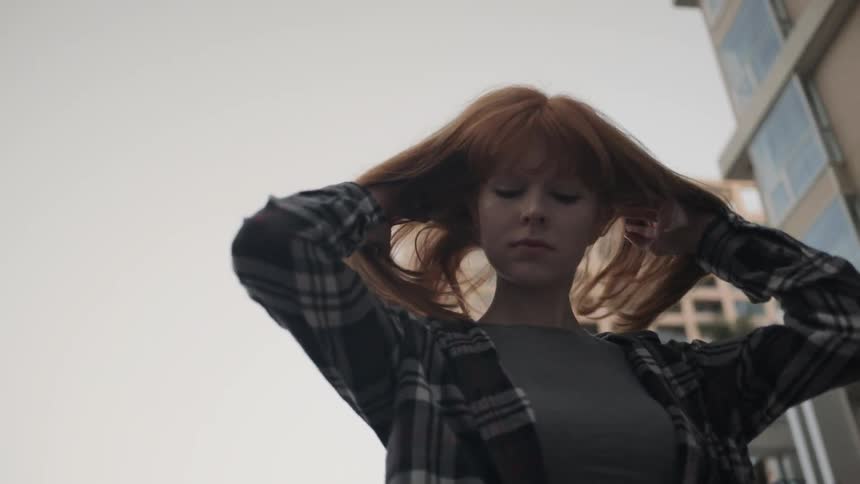 A red haired woman throws her hair over her shoulders