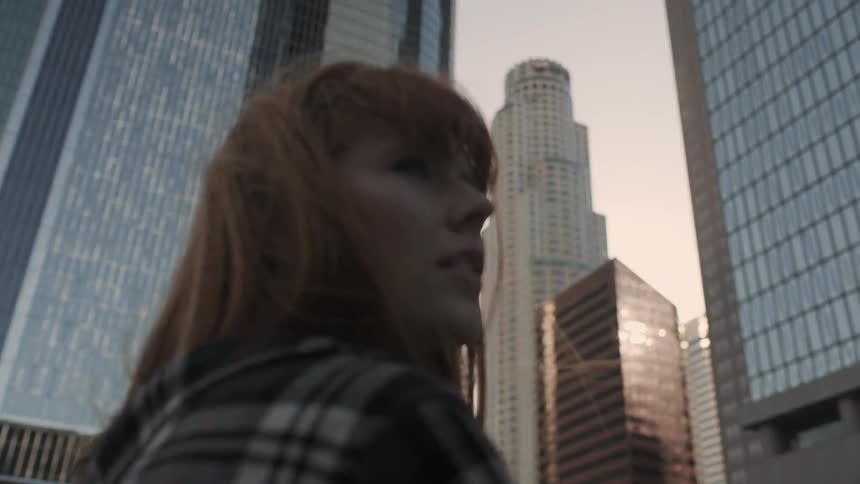 A red haired woman walks outside in the city