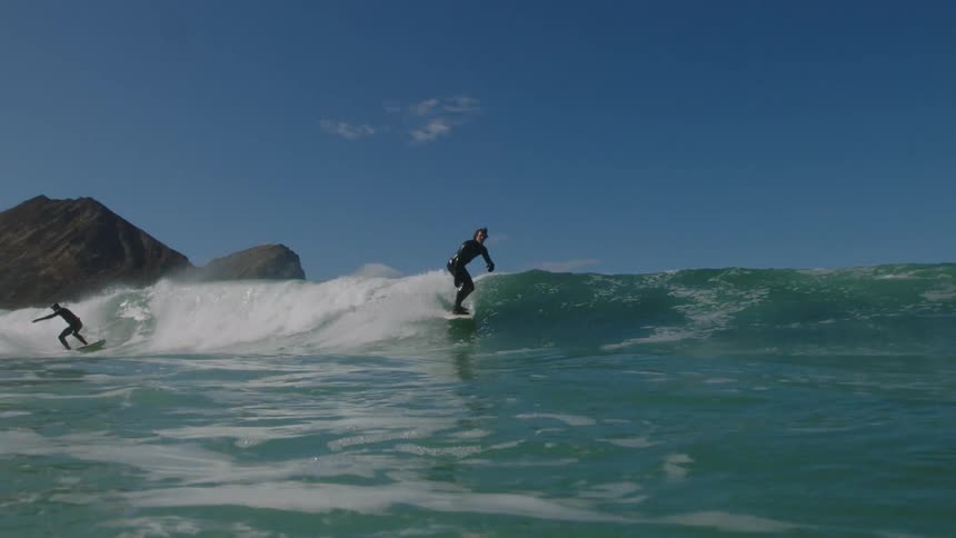 Surfers ride a wave on a sunny day
