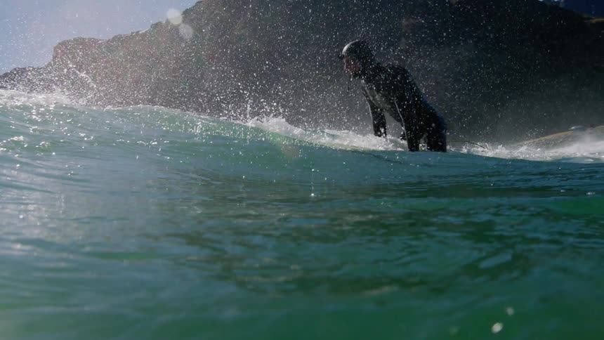 A man floats on a surfboard in a wet suit