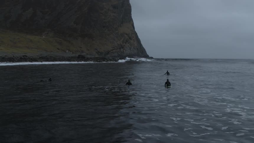 Surfers float in the water near the shore