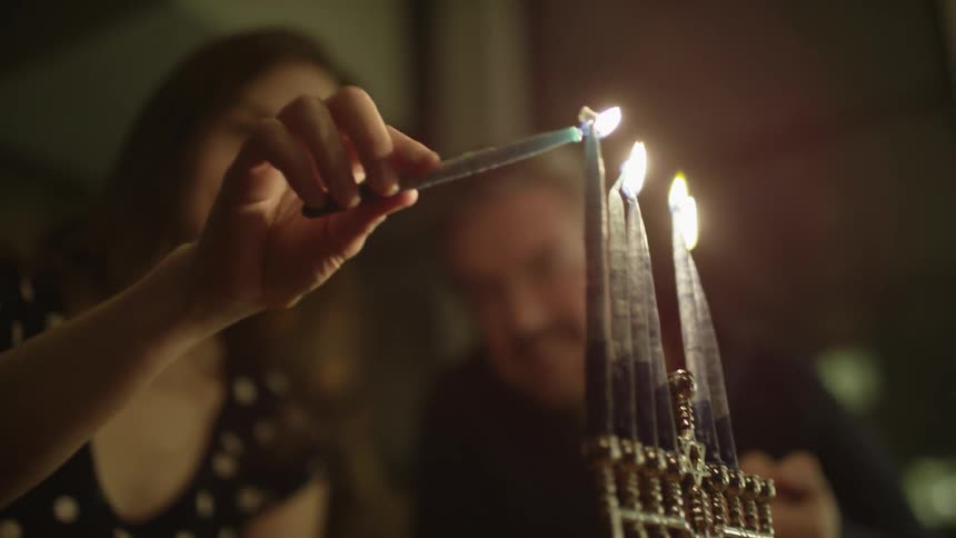 A woman lights a menorah