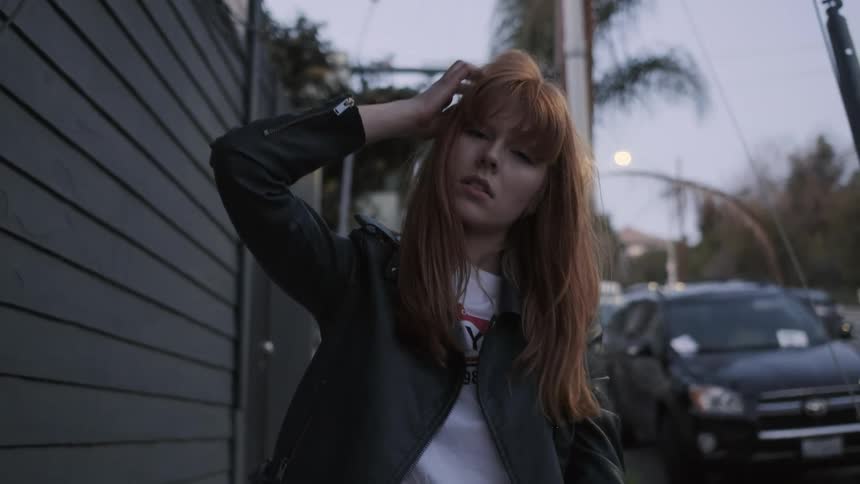 A red haired woman stands out on the sidewalk