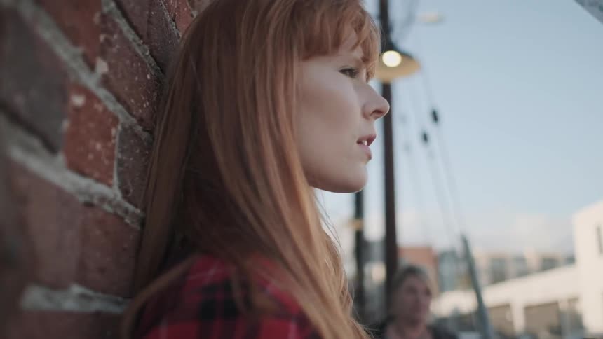 A woman is leaning up against a wall and observing the city around her