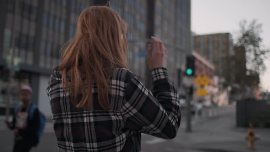 A red haired woman walks outside in the city