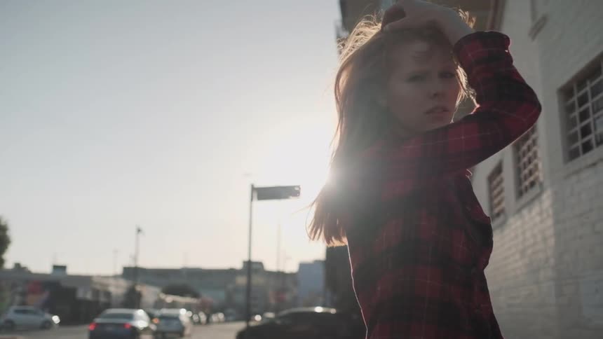 A red haired woman stands outside in the sun