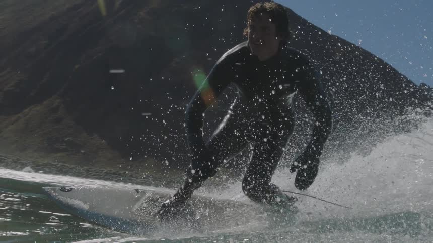 A surfer rides a wave near the shore