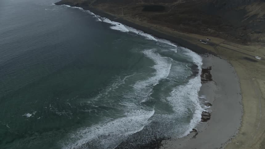 Waves roll toward a beach on a cloudy day