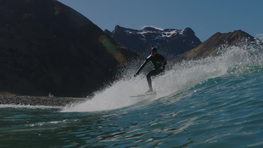 A surfer rides a tall wave near the shore
