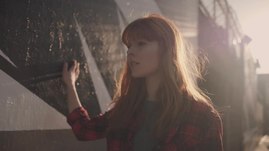 A red haired woman wipes her hand on a wall as she walks by