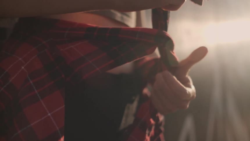 A woman ties a flannel shirt around her waist