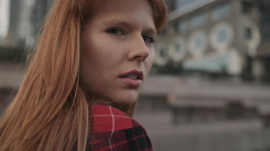 A woman standing on a roof in the city is looking over her shoulder