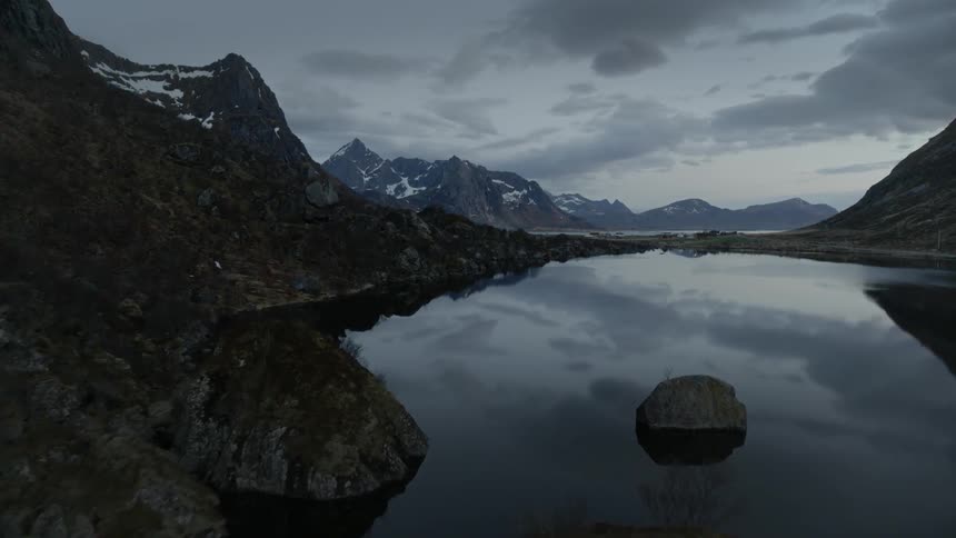 A mountain lake reflects the sky and mountain landscape at dusk