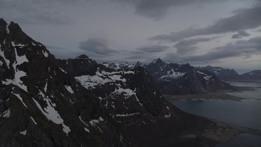 Snow dots the peaks of a coastal mountain range at dusk