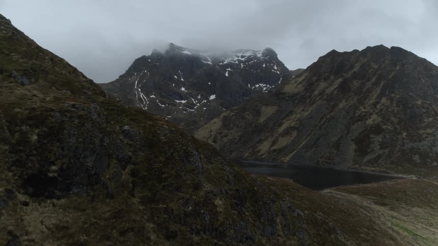 Fog and clouds hang above the snowy mountains