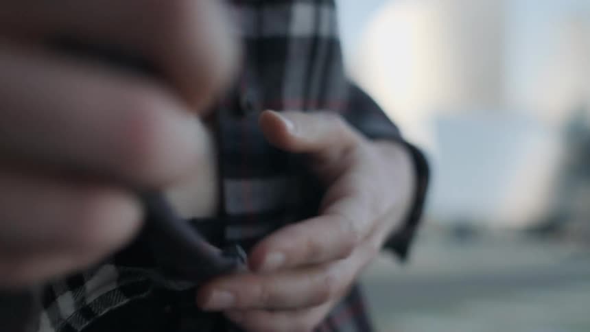 A woman is unbuttoning her shirt as she stands outside