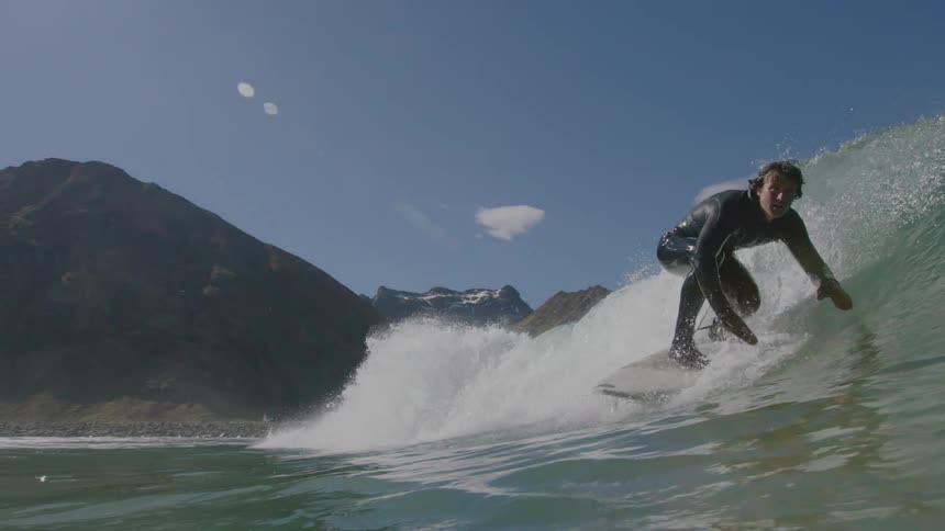 A surfer catches a wave on a sunny day