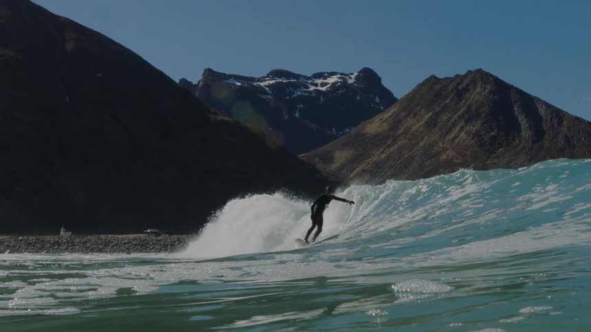 A surfer rides a tall wave near the shore
