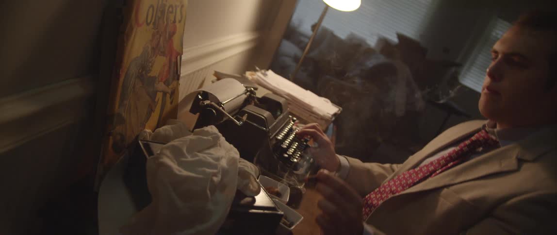 A man smoking at a typewriter