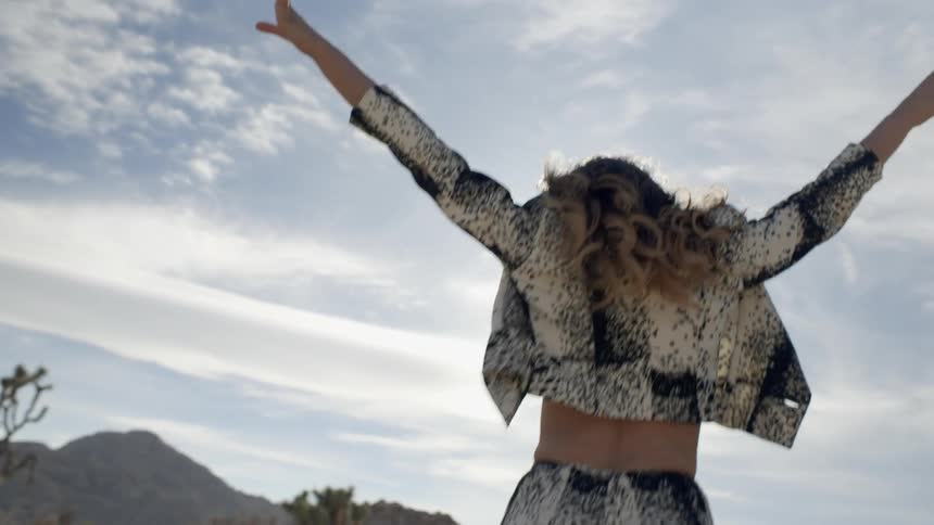 A woman jumps for joy out in the sun