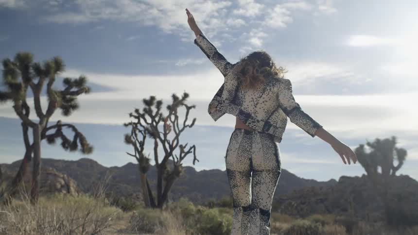 A woman walks happily out in the desert