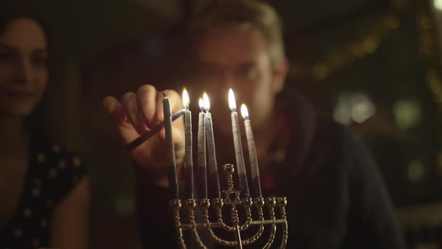 Man and woman lighting a menorah