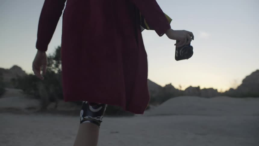 Woman walks on the sand as she carries a camera