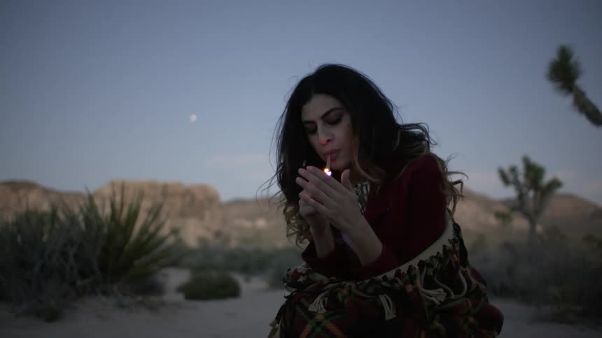 A woman lights a cigarette outside