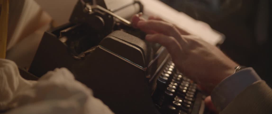 Person in suit typing on vintage typewriter