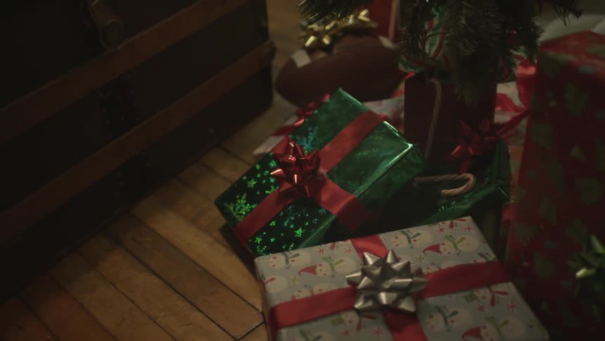 Christmas gifts are piled under a tree