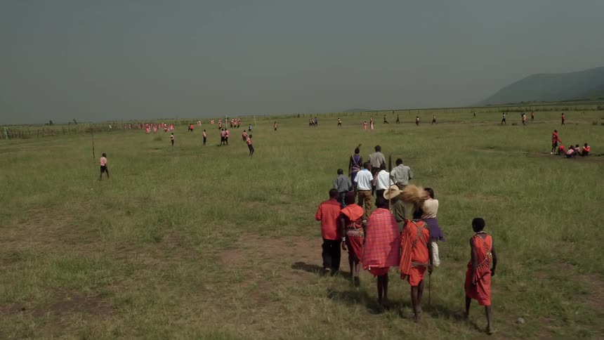 Tourists accompany maasai as they gather in an open field