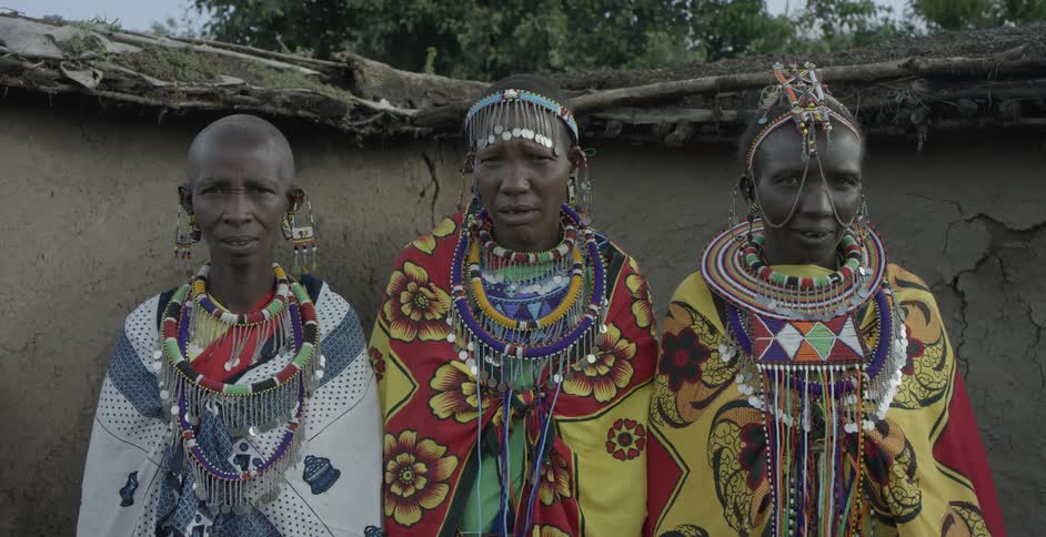 Maasai people stand outside their village displaying their native costumes